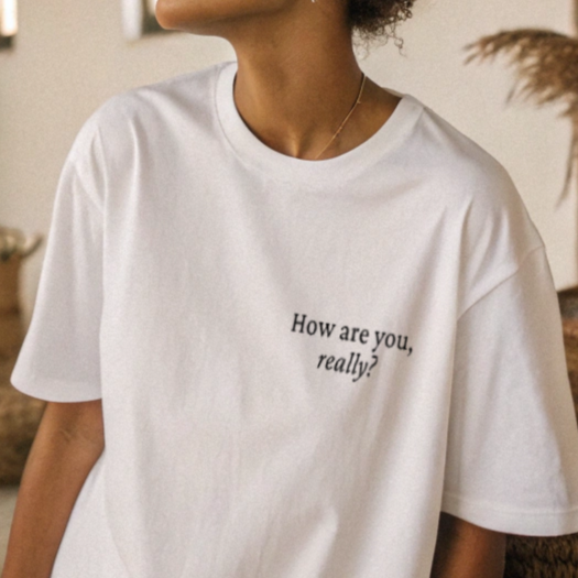Person wearing a white t-shirt with "How are you, really?"