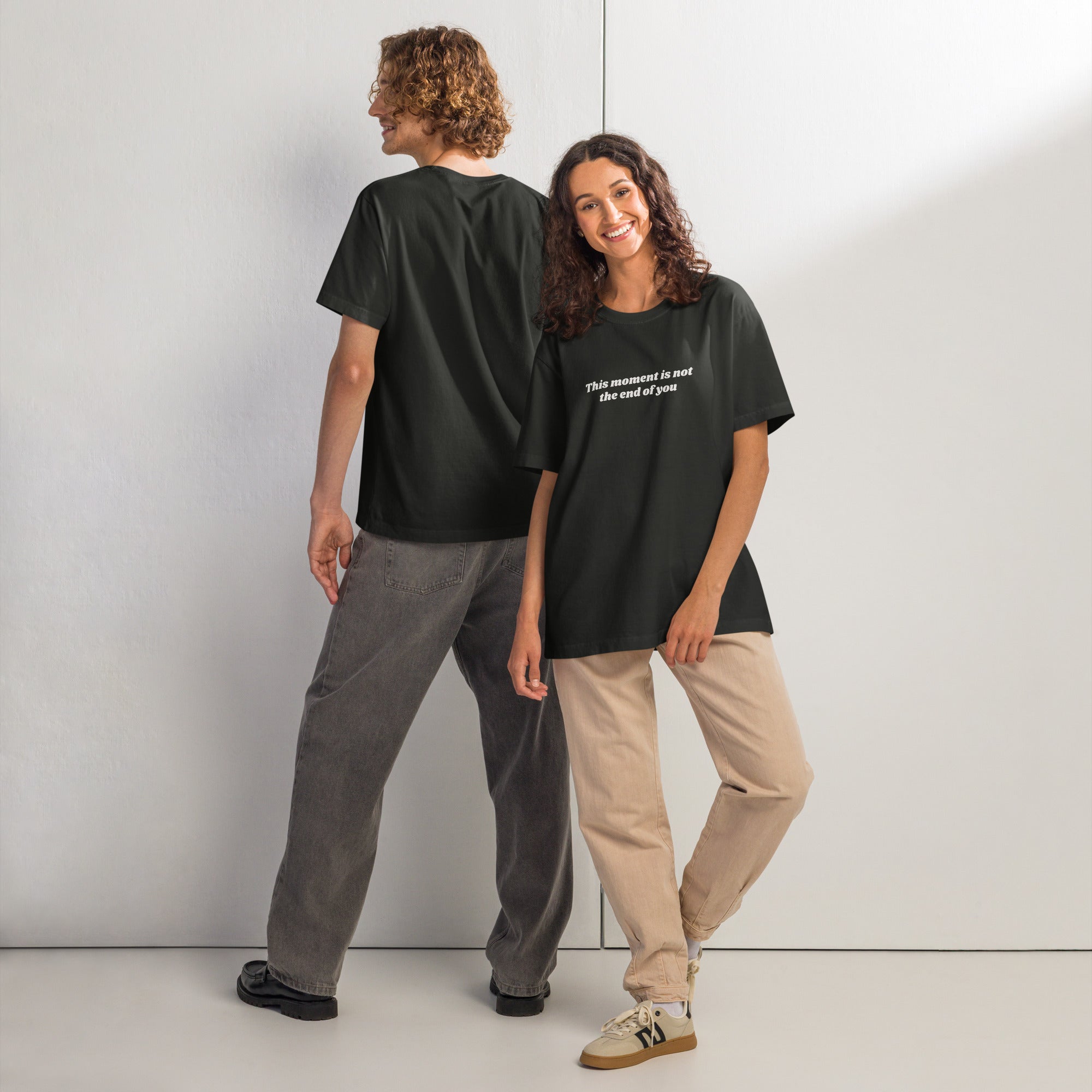 Two people wearing black t-shirts with motivational quote “This Moment Is Not the End of You” reminder affirmation for resilience and healing.