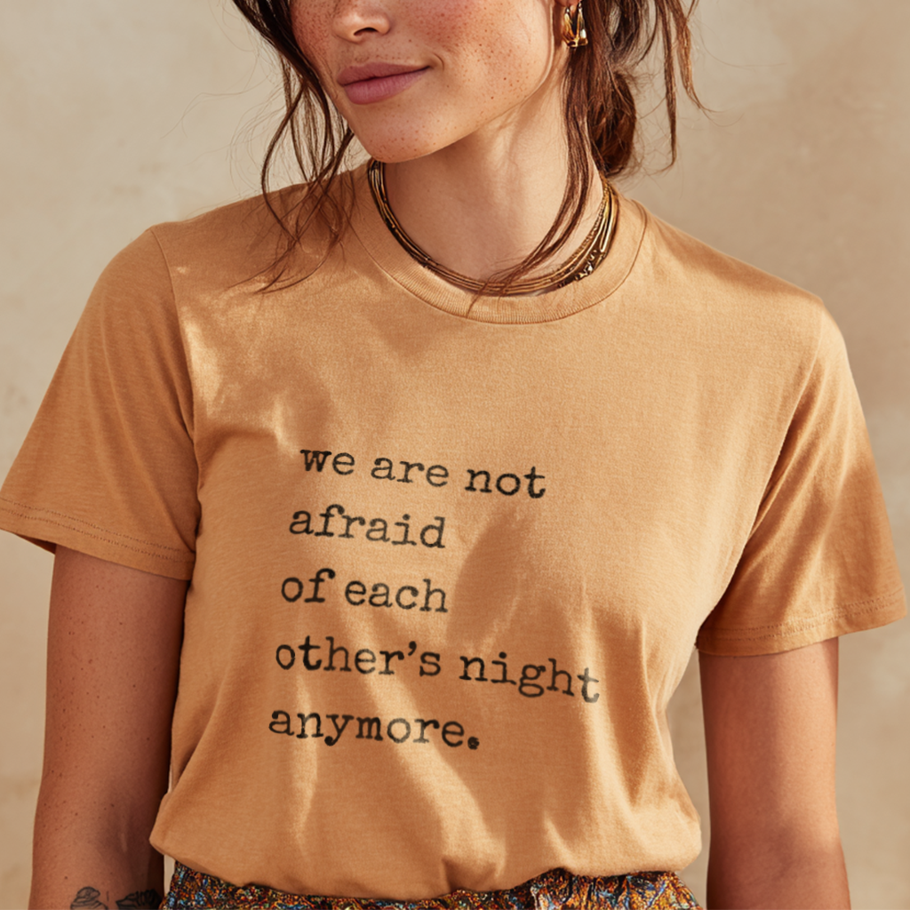 Person wearing a tan t-shirt with a motivational quote &quot;we are not afraid of each other&